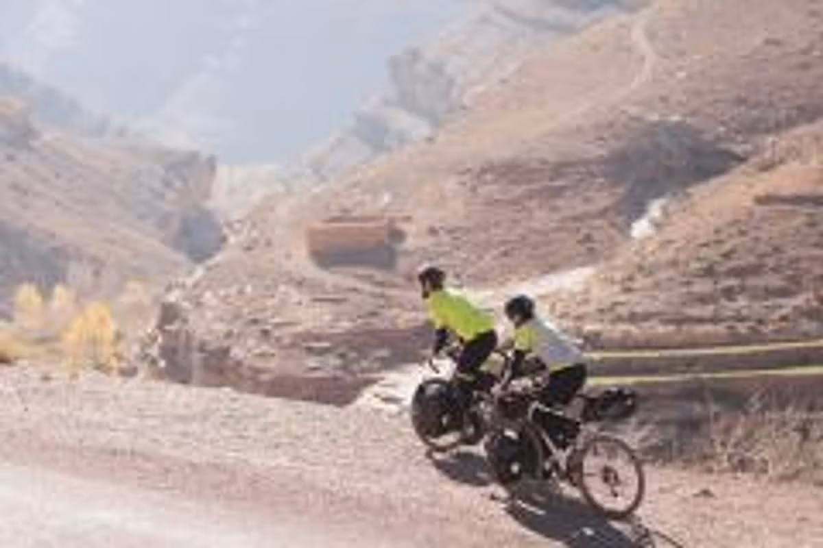 A cyclist on a dirt track above a hazy Atlas gorge