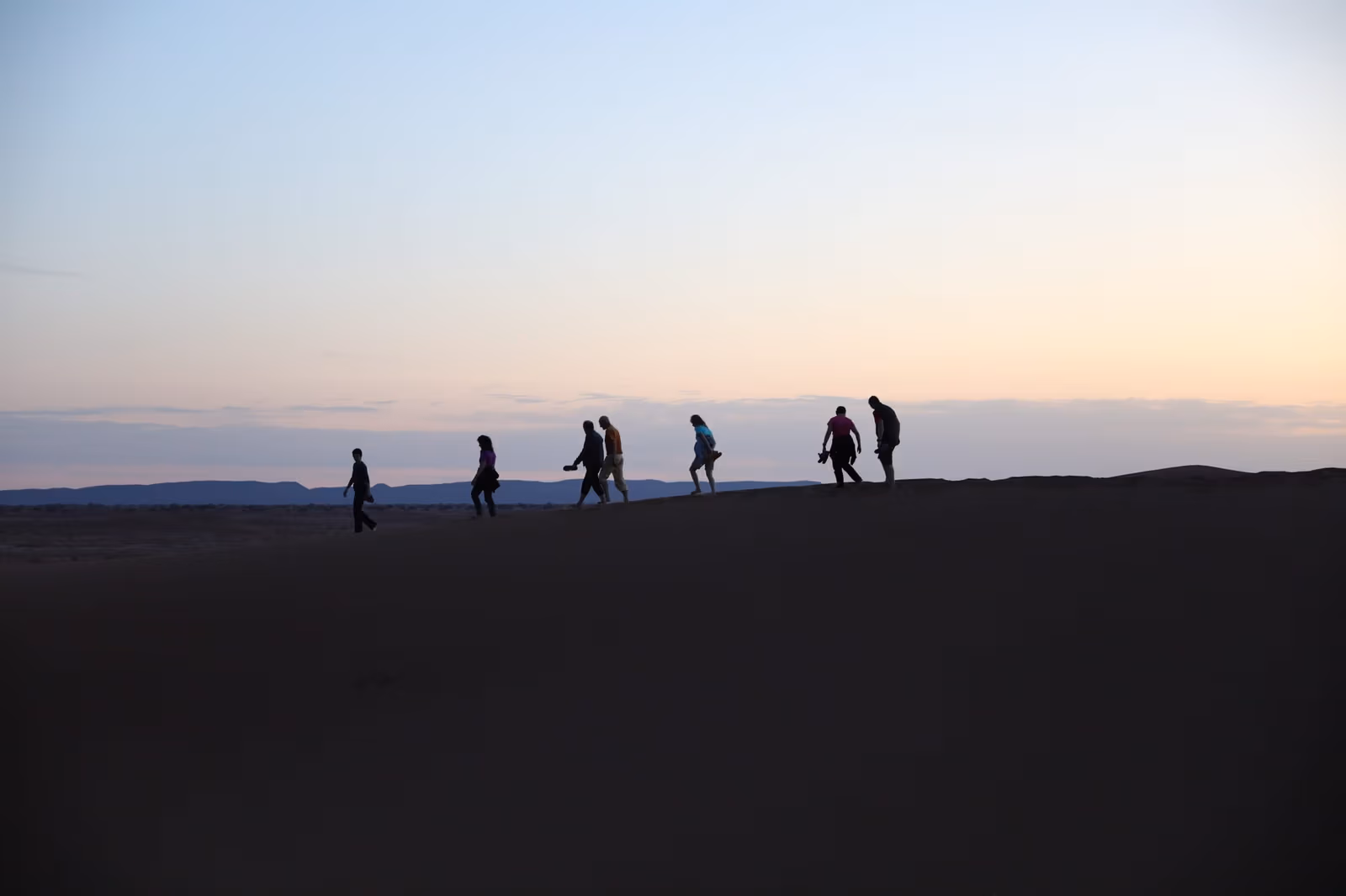 Trekkers silhouetted on a ridge at dusk in the High Atlas